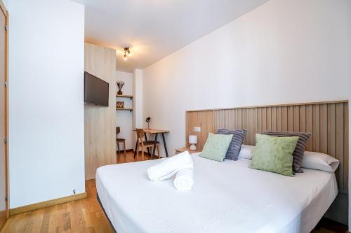 a bedroom with a large white bed and a table at Allotjament el Pont in Camprodon
