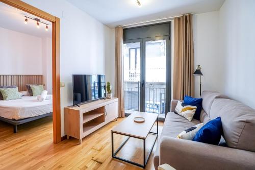 a living room with a couch and a tv and a bed at Allotjament el Pont in Camprodon