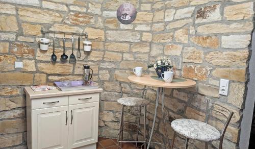a kitchen with a stone wall with a table and stools at Romantik Ferienhaus 1854 in Elpe
