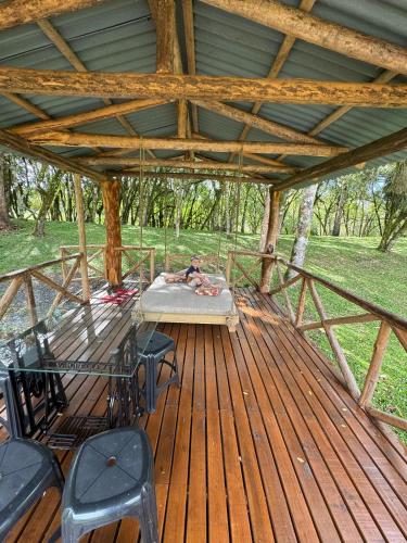 a man laying on a bed on a wooden deck at Pousada Caminho do Lago in Rio Rufino