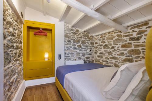 a bedroom with a bed and a stone wall at Larimis House in Loutraki