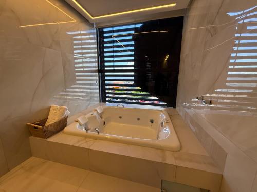a white bath tub in a bathroom with a window at Hotel London Santarem in Santarém