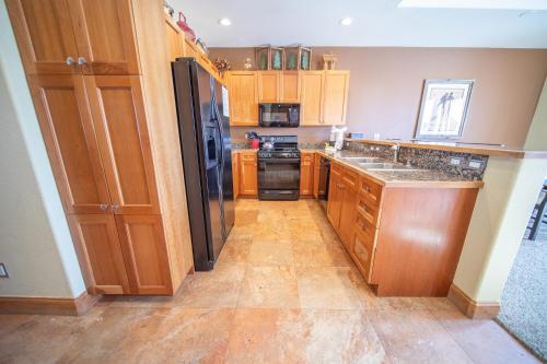 a kitchen with wooden cabinets and a black refrigerator at Antlers Gulch 303 by SummitCove Lodging in Colorado in Keystone