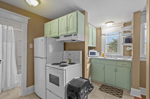 a kitchen with green cabinets and a white refrigerator at Chic Midstream Studio WiFi Parking in St. John's