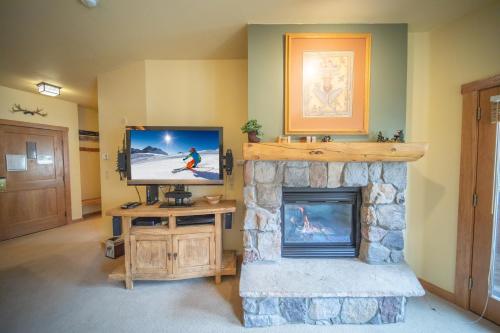a living room with a fireplace and a television at Arapahoe Lodge 8116 by SummitCove Lodging in Keystone