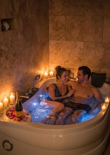 a man and woman sitting in a bathtub with candles at Romance Bleue -Love Room -SPA privatif - Netflix -séjour à vichy in Vichy
