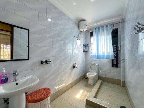 a white bathroom with a sink and a toilet at NL Josephine's Hotel, Apartment in Kampala