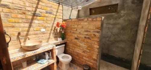 a bathroom with a toilet and a brick wall at Finca El Recuerdo in Guatavita