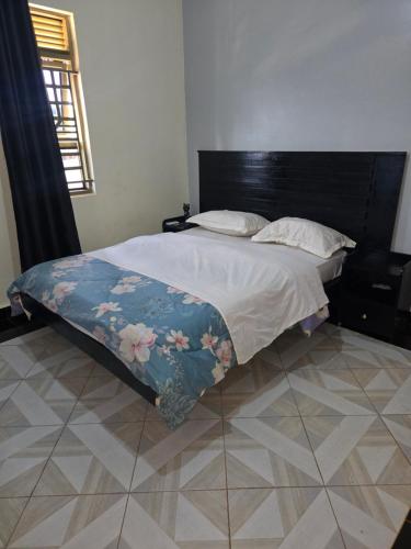 a bedroom with a bed with a floral blanket on it at Dorah's Apartment in Entebbe