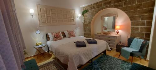ein Schlafzimmer mit einem Bett, einem Spiegel und einem Stuhl in der Unterkunft Tsaner Apartment and Rooms in Matala