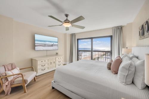 a bedroom with a bed and a tv and a window at Sunrise beach views with top complex amenities and pool access! in Ormond Beach