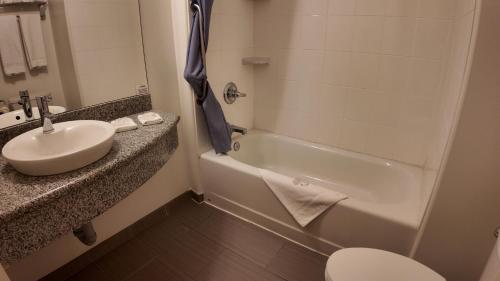 a bathroom with a sink and a tub and a toilet at Wilshireinn Hotel in Claresholm