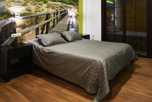 a bed in a bedroom with a painting of a bridge at Hostal Boutique El Patio Lepe in Lepe