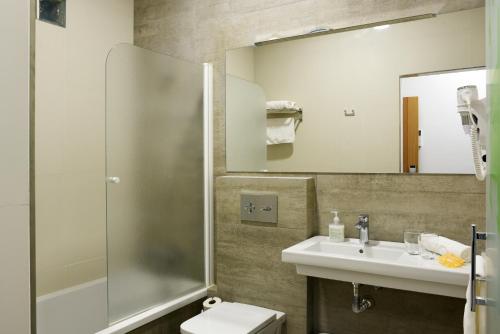 a bathroom with a sink and a toilet and a mirror at Hostal Boutique El Patio Lepe in Lepe