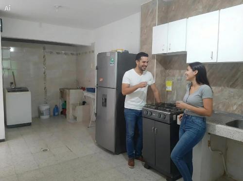 a man and woman standing in a kitchen with a stove at Mom's House Floralia in Cali