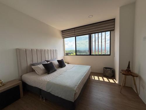 a bedroom with a bed and a large window at Modern Apartment With Espectacular Panoramic Views in Pereira