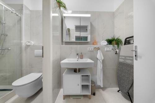 a white bathroom with a sink and a toilet at Loftly Modersohnstr nähe East Side Gallery nähe Uber Arena in Berlin