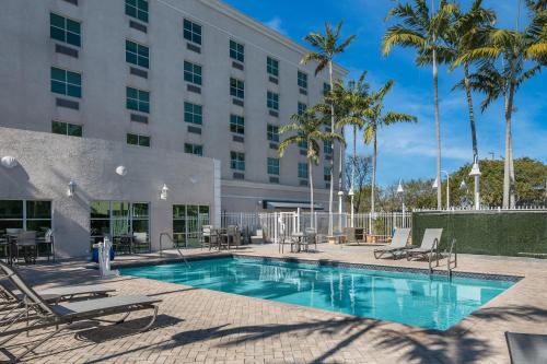 a pool at a hotel with chairs and palm trees at Holiday Inn Express & Suites Miami Kendall by IHG in Kendall