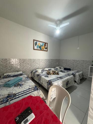 a room with two beds and a table with a remote control at Aconchego Sagrada face 2 in Aparecida