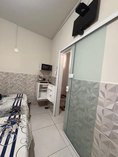 a small room with two beds and a shower at Aconchego Sagrada face 2 in Aparecida