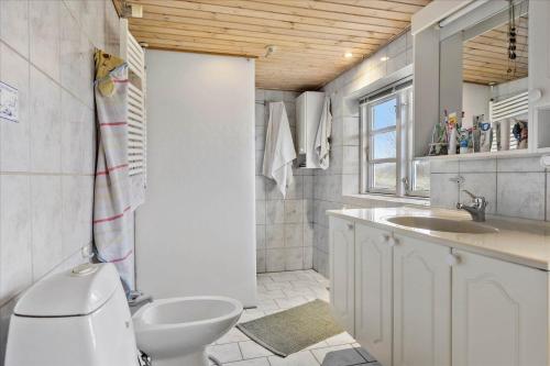 a white bathroom with a toilet and a sink at Ferienhaus Sommer in Nordborg