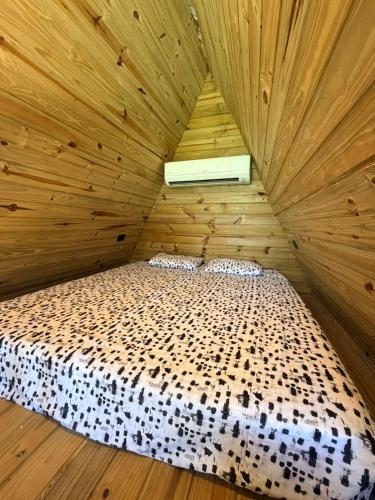 a bedroom with a bed in a wooden room at Chalé Bruma in Pouso Alegre