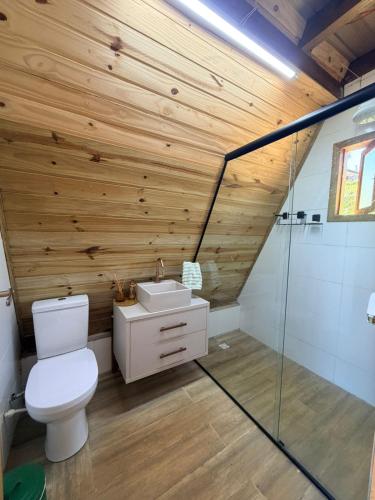 a bathroom with a white toilet and a wooden wall at Chalé Bruma in Pouso Alegre
