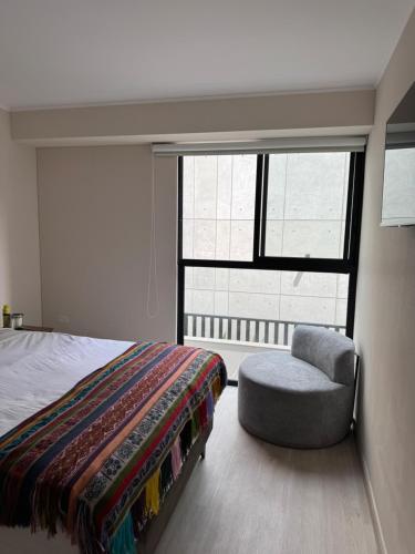 a bedroom with a bed and a chair and a window at Miraflores Loft Piscina in Lima