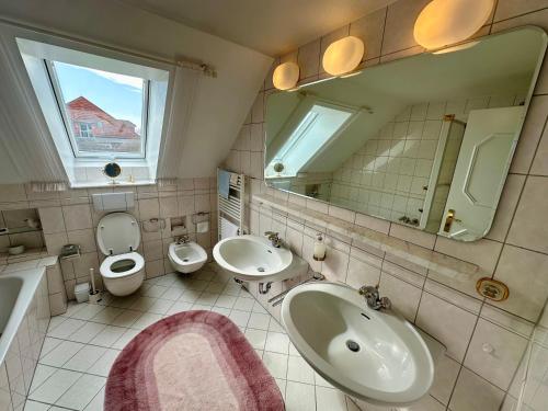 a bathroom with two sinks and a toilet and a mirror at Südblick 1 in Fehmarn