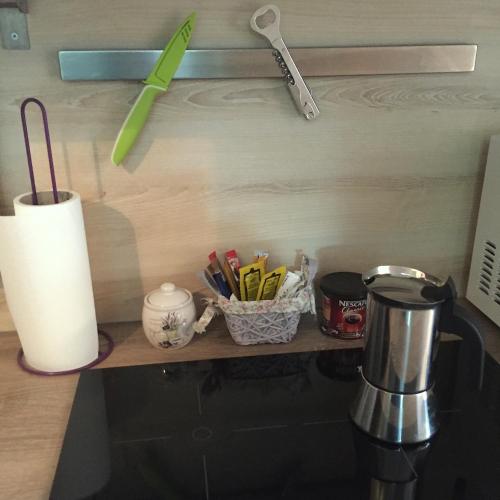 a kitchen counter with a shelf with a coffee pot and utensils at Mikes Apartman in Szekszárd