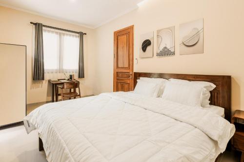 a bedroom with a large white bed and a desk at Sakabumi Home in Ngabean