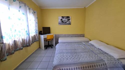 a bedroom with two beds and a desk with a computer at Yellowkits in São Paulo
