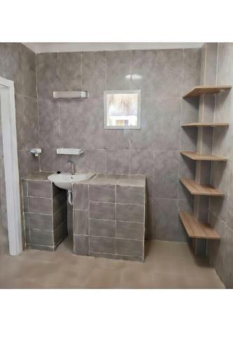 a bathroom with a sink and a shelf at A La Teranga in Poundiougne