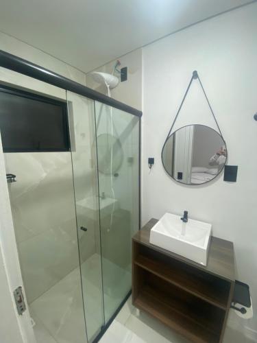 a bathroom with a shower and a sink and a mirror at Pousada Vale das Bromelias Termas do Gravatal in Gravatal