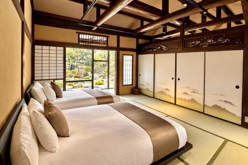two beds in a room with large windows at 宮島 Shinwa in Miyajima
