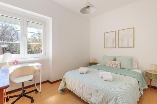 a white bedroom with a bed and a desk and a window at Lovely Apartment to Stay in Lisbon