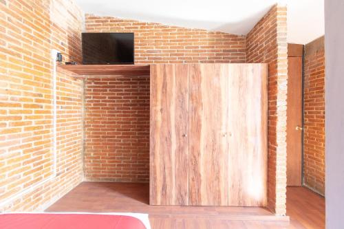 a wooden door in a brick wall with a tv at Hotel de Guadalupe, Puebla in Puebla