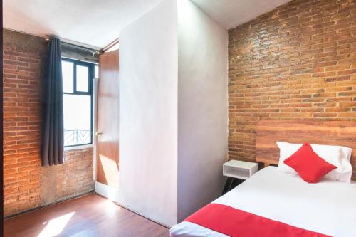 a room with a bed and a brick wall at Hotel de Guadalupe in Puebla