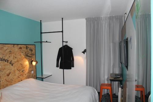 a bedroom with a bed and a dresser and a television at The Originals Access, Hôtel Clermont-Ferrand Nord in Châteaugay