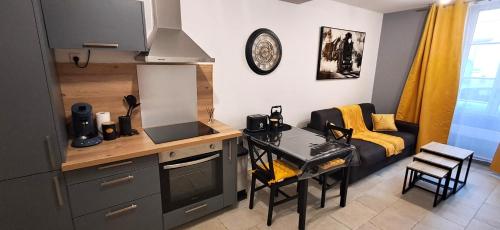 a kitchen with a table and a couch in a room at Le Petit Jaune in Orthez