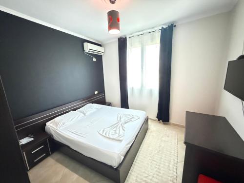 a small bedroom with a bed with white sheets at Hotel corner in Bërzhitë