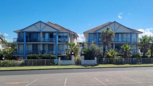 a blue house with palm trees in front of a street at Apartment In Paradise in Hawks Nest