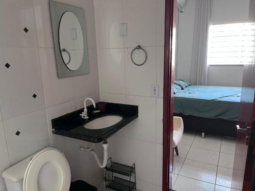 a bathroom with a sink and a toilet and a bed at Casa jardim fonte nova in Goiânia