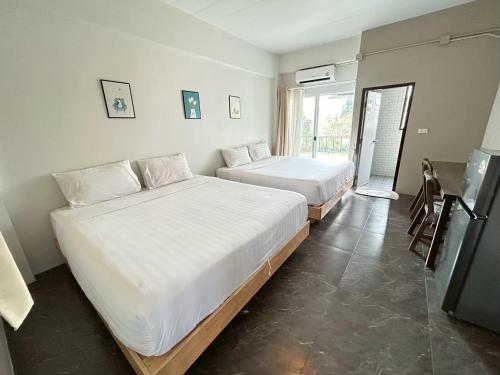 a bedroom with two beds and a table and a window at Comfy hotels Soi Kingkeaw31ก Alley ซอยกิ่งแก้ว31ก in Suvarnabhumi Airport