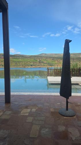 a black umbrella standing in front of a body of water at Le Figuier du Lac Bin elouidane in Bine el Ouidane