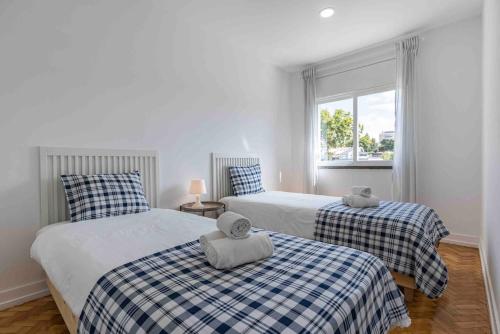 two twin beds in a room with a window at Carcavelos Village III By Staycalm in Carcavelos