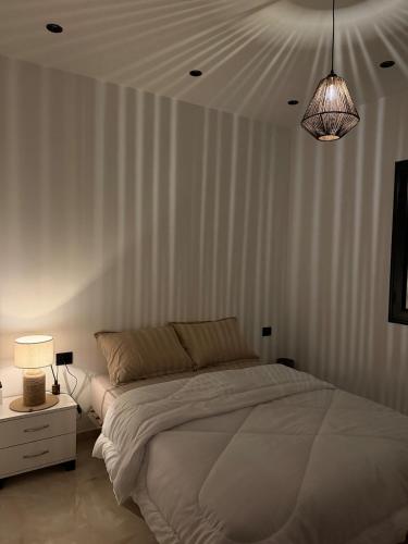 a white bedroom with a bed and a lamp at Nestlya Apartment in Sukrah