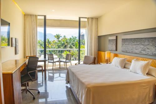 a hotel room with a large bed and a desk at Hotel Mio Vallarta - Adults Only in Puerto Vallarta