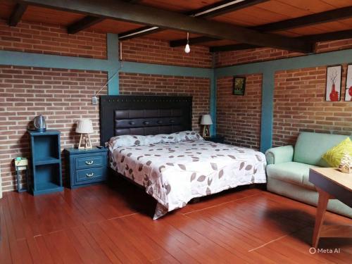 a bedroom with a bed and a couch and a brick wall at CABAÑA Adán y Eva en Zacatlán in Zacatlán