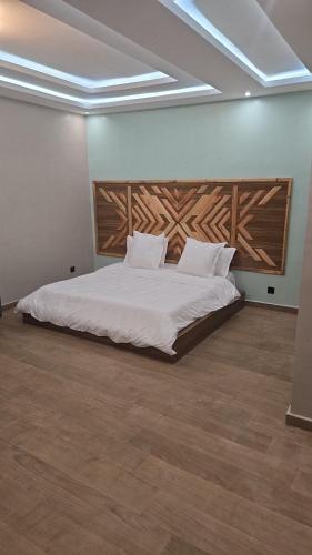 a bedroom with a white bed with a wooden headboard at Ouakam Monument de la Renaissance 2 in Dakar